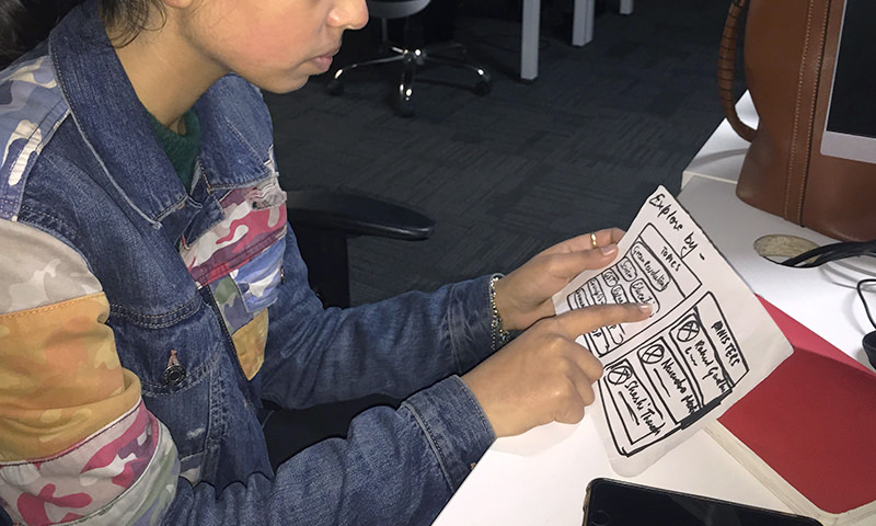 A user interacting with a paper prototype to identify exploration preferences, i.e., exploring by topics vs. exploring by politicians.